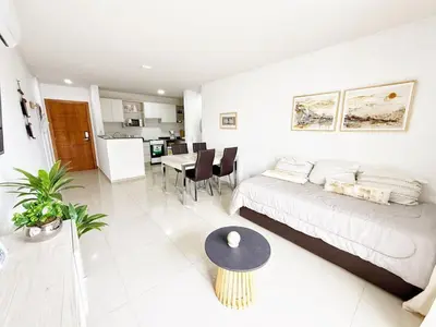 a white living room with a couch and a table at OPERA Apartamentos in Villa Carlos Paz