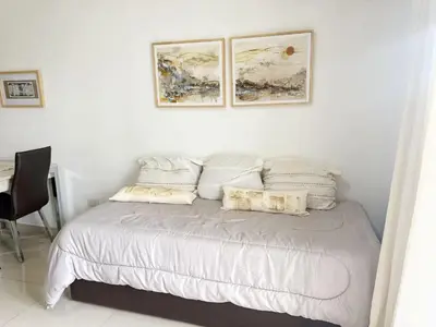 a white bedroom with a bed with two pictures on the wall at OPERA Apartamentos in Villa Carlos Paz