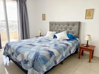 a bedroom with a bed with a blue and white comforter at OPERA Apartamentos in Villa Carlos Paz