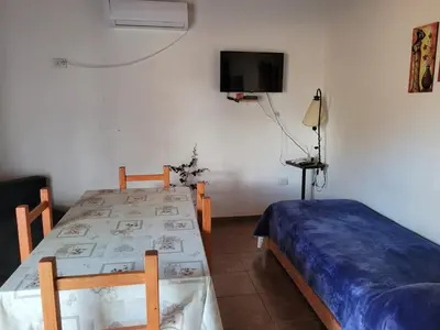 a bedroom with two beds and a tv on the wall at Confortable Casa con Pileta, Parrilla y Patio in Cruz de Caña