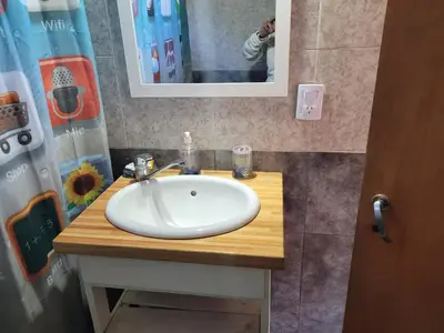 a bathroom with a white sink and a mirror at Confortable Casa con Pileta, Parrilla y Patio in Cruz de Caña