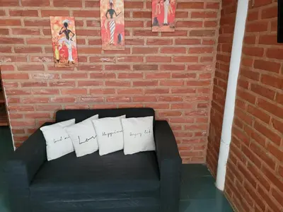 a black couch with three pillows on it next to a brick wall at Confortable Casa con Pileta, Parrilla y Patio in Cruz de Caña