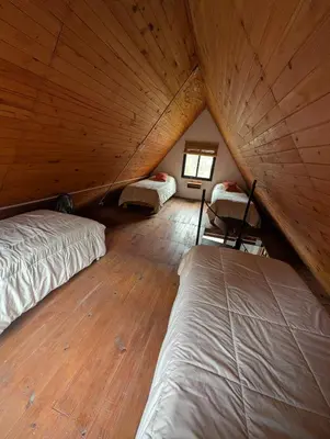 a bedroom with two beds in a wooden attic at Cabañas Terra in Villa Yacanto