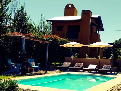 a swimming pool with chairs and umbrellas next to a house at La Cambicha Ranchos in Los Reartes