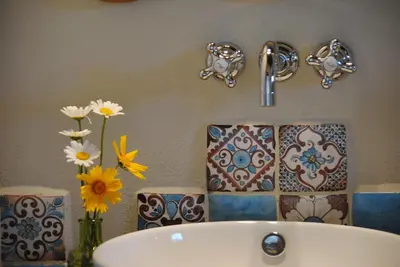 a bathroom with a sink and flowers on the wall at La Cambicha Ranchos in Los Reartes