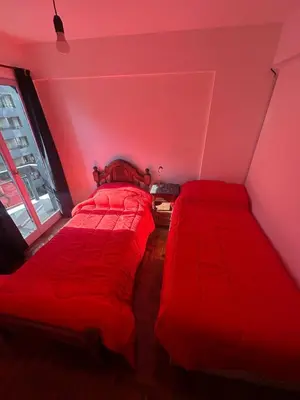 two beds in a room with red sheets at Estrada Apart in Cordoba