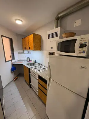 a kitchen with a white refrigerator and a microwave at Apartamento en Pleno Nueva Córdoba, Garzon, By ApartCba in Cordoba