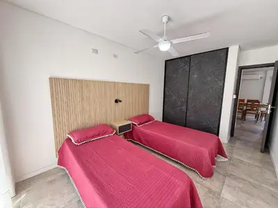 two beds in a room with red sheets at Edificio Catalina in Villa Carlos Paz