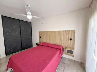 a bedroom with a pink bed and a ceiling fan at Edificio Catalina in Villa Carlos Paz