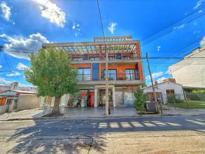 a building on a street with a tree in front of it at Edificio Catalina in Villa Carlos Paz