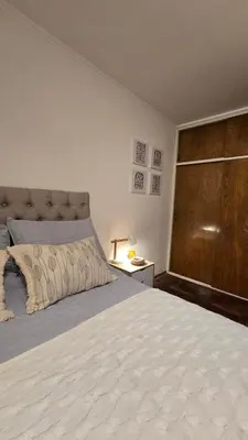 a bedroom with a large bed and a wooden door at Departamento Nueva Córdoba - Parque Sarmiento in Cordoba