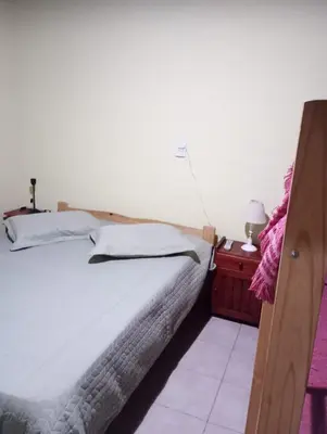 a bedroom with a large bed and a night stand at Cabañas Los Abuelos in Santa Rosa de Calamuchita