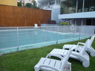 a group of white benches sitting next to a swimming pool at Del Vaiven in Villa Carlos Paz