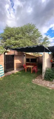 a patio with a table and red chairs in a yard at Los Horneros in Villa Cura Brochero