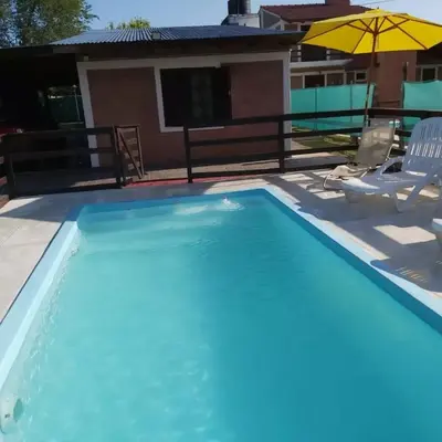 a swimming pool with a house in the background at Cabañas Los Abuelos in Santa Rosa de Calamuchita