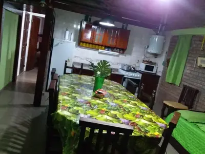 a kitchen with a table with a green table cloth at Cabañas Los Abuelos in Santa Rosa de Calamuchita