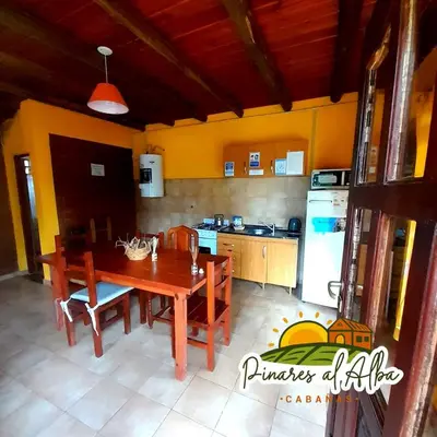 a kitchen with a wooden table and a dining room at Cabañas Pinares al Alba in Almafuerte