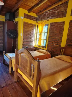 a bedroom with two beds in a room with a brick wall at Cabañas Pinares al Alba in Almafuerte