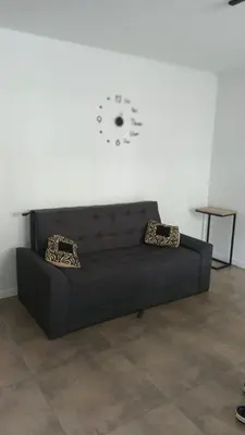 a black couch in a room with a clock on the wall at Departamento Lake Towers in Villa Carlos Paz