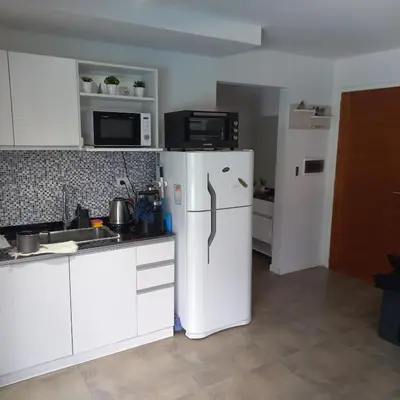 a kitchen with a white refrigerator and a microwave at Departamento Lake Towers in Villa Carlos Paz