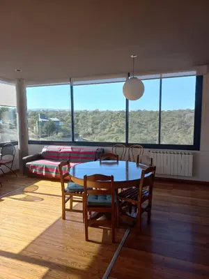a living room with a table and chairs and a bed at CuyenCo in Santa Rosa de Calamuchita