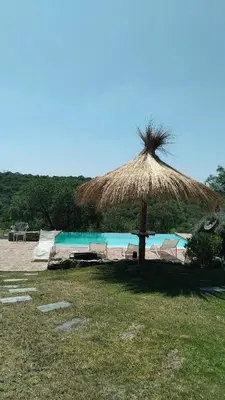 a straw umbrella on a beach with a pool at CuyenCo in Santa Rosa de Calamuchita