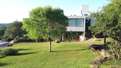 a house on a hill with a tree in front of it at CuyenCo in Santa Rosa de Calamuchita