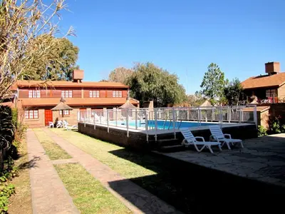 a swimming pool with two chairs next to a house at Complejo Steffen in Merlo