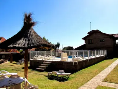 a resort with a pool with chairs and an umbrella at Complejo Steffen in Merlo