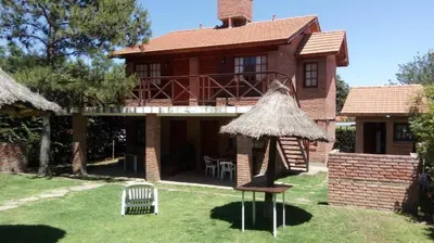 a brick house with a deck and a chair in the yard at Complejo Steffen in Merlo