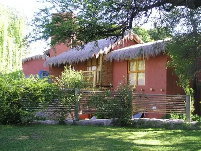 a red house with a bench in front of it at Posada La Valentina in Villa de Las Rosas