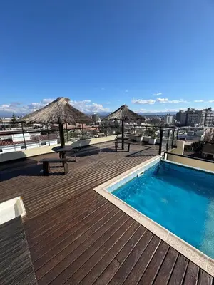 a deck with a swimming pool and umbrellas on a building at Carlos Paz Roque Sainz Peña in Villa Carlos Paz