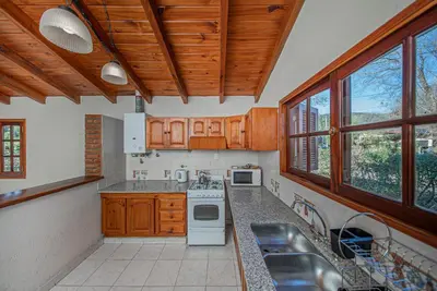 a kitchen with wooden cabinets and white appliances at Cabañas Montecarlo 1 in Santa Rosa de Calamuchita