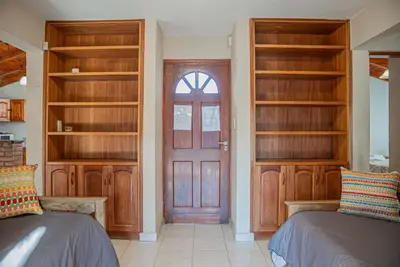 a room with two beds and a door with shelves at Cabañas Montecarlo 1 in Santa Rosa de Calamuchita