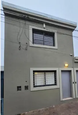 a white building with two windows and a door at Hermoso Departamento Planta Baja in Cordoba