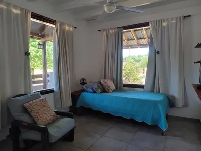 a bedroom with a bed and a chair and a window at Cabañas Finca del molino in Panaholma