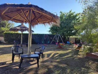 a playground with chairs and an umbrella and swings at Cabañas Finca del molino in Panaholma
