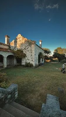 an old stone building with people sitting in a yard at Estancia Saldañil in Villa Los Aromos