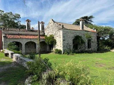 an old stone house with a grass yard at Estancia Saldañil in Villa Los Aromos