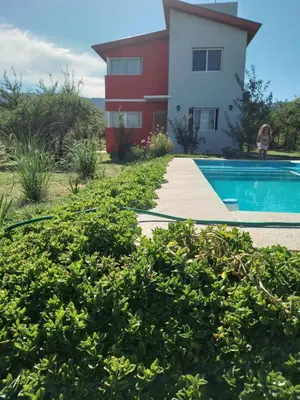 a house and a swimming pool in front of a house at Cabañas Merlina in Cortaderas