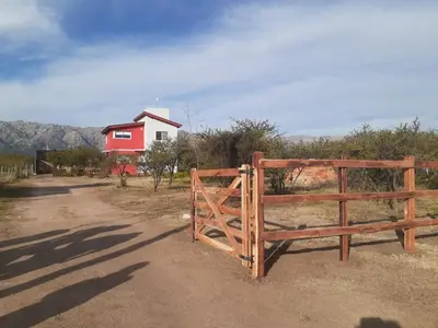 a wooden gate in front of a red house at Cabañas Merlina in Cortaderas