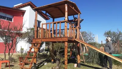 a man standing in front of a wooden play structure at Cabañas Merlina in Cortaderas