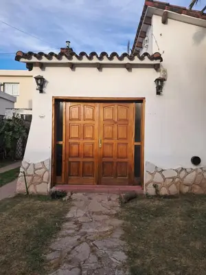 a white house with a wooden garage door at La Casa de María Helenra in Alta Gracia