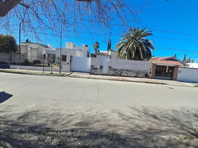 an empty street with a house and a palm tree at La Casa de María Helenra in Alta Gracia