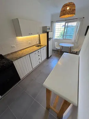 a kitchen with a white refrigerator and a table at Duplex 1 Dormitorio Costa Azul in Villa Carlos Paz