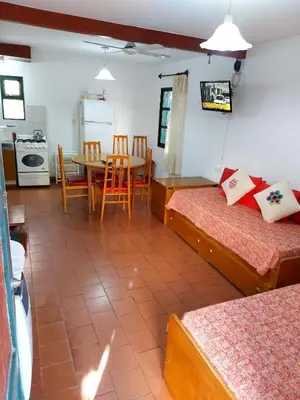 a room with two beds and a table and a kitchen at Castillo Del Lago - Carlos Paz - D19 in Villa Carlos Paz