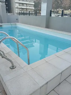 a swimming pool with blue water in a building at Depto Centrico Etoile 4 in Villa Carlos Paz
