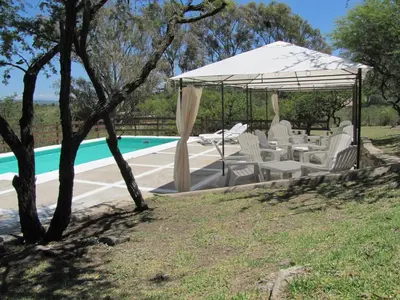 a group of chairs under a canopy next to a pool at Cabañas El Mirador in Embalse