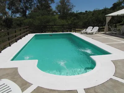a swimming pool with two chairs and a table at Cabañas El Mirador in Embalse