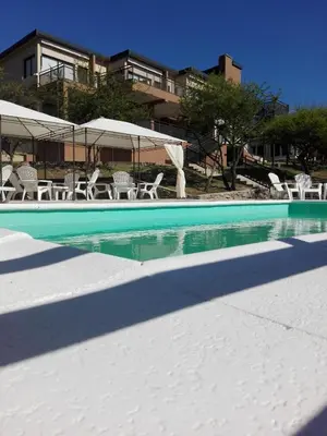 a swimming pool with chairs and umbrellas next to a building at Cabañas El Mirador in Embalse